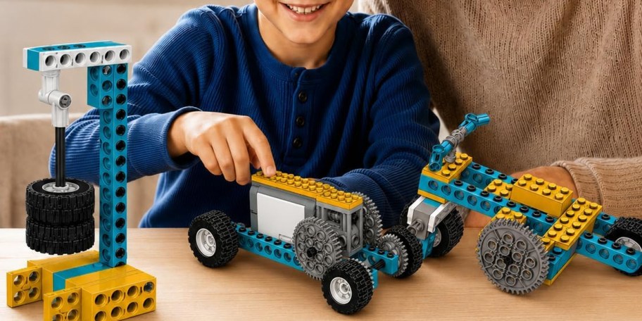kid in blue tee playing with blue and yellow building science kit on table