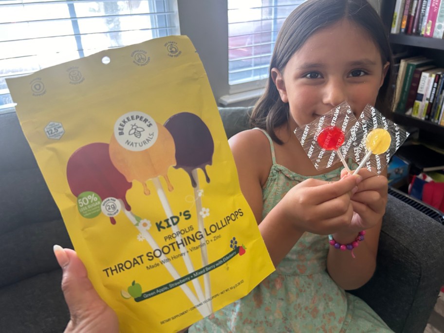 hand holding bag of lollipops in front of girl