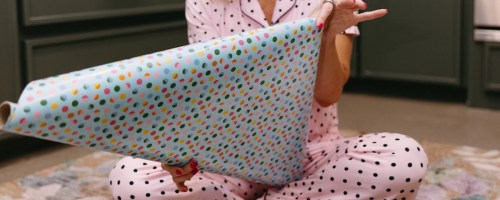 Woman sitting on carpet wrapping Christmas gifts