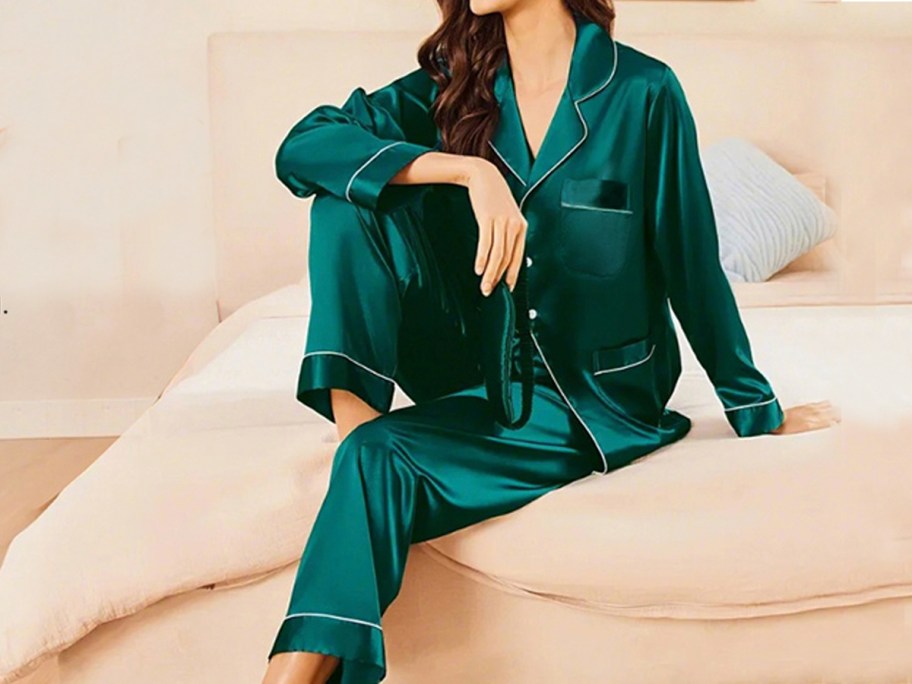 woman wearing dark green silk pajama set on bed