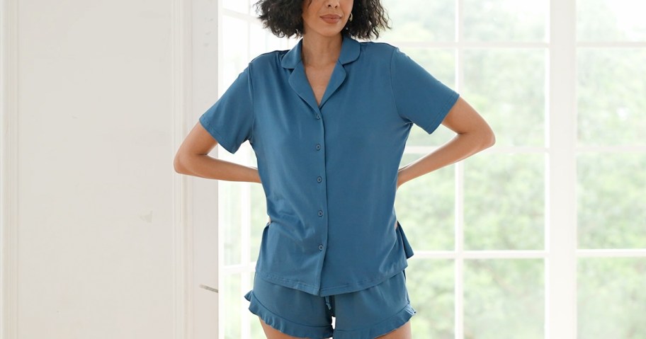 woman wearing short sleeve and shorts blue pajama set in front of window