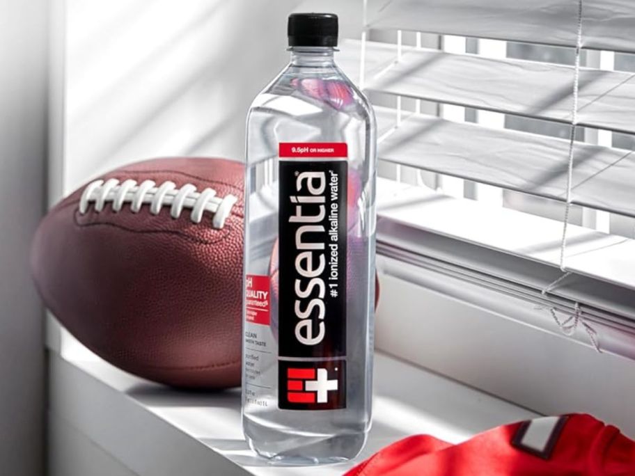 essentia water bottle in front of foot ball