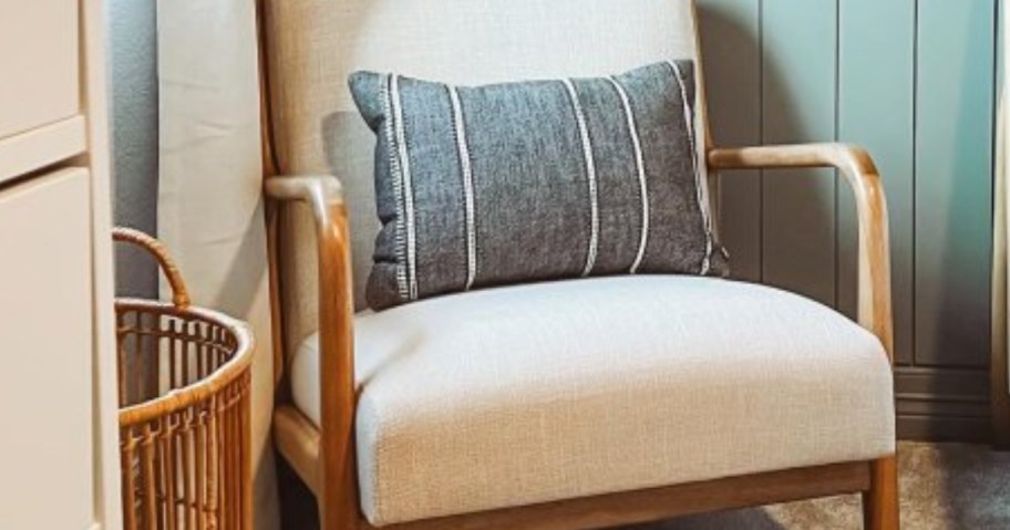 black, grey, and white stripe throw pillow in a wood chair with cream cushions