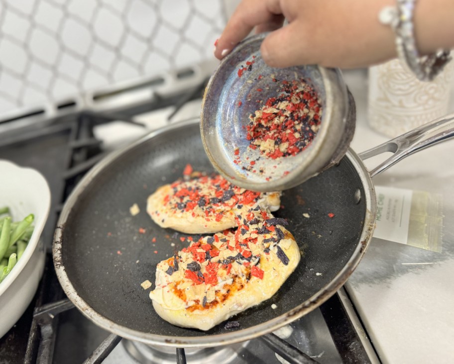 hand pouring topping on chicken