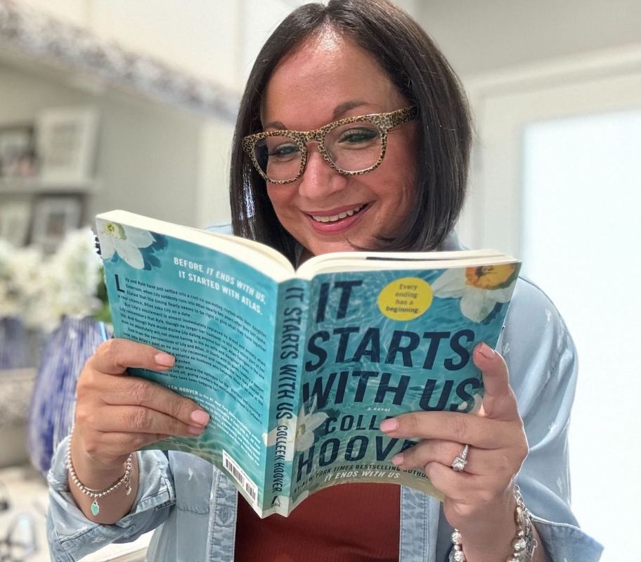 woman holding it starts with us book wearing stylish glasses