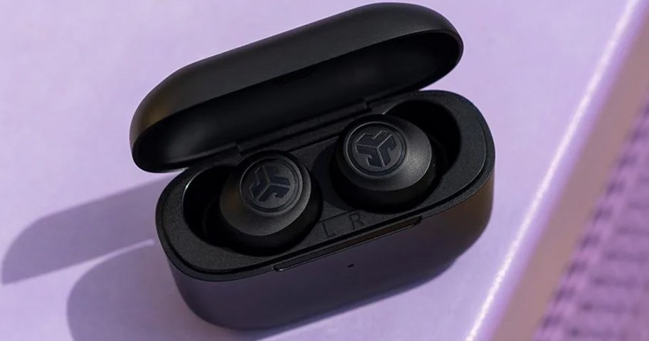 black jlab earbuds in charging case on purple table