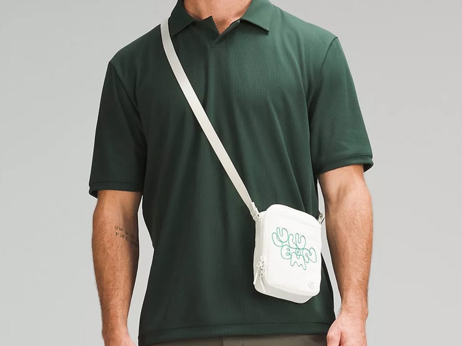 man in a dark green polo with a white crossbody bag