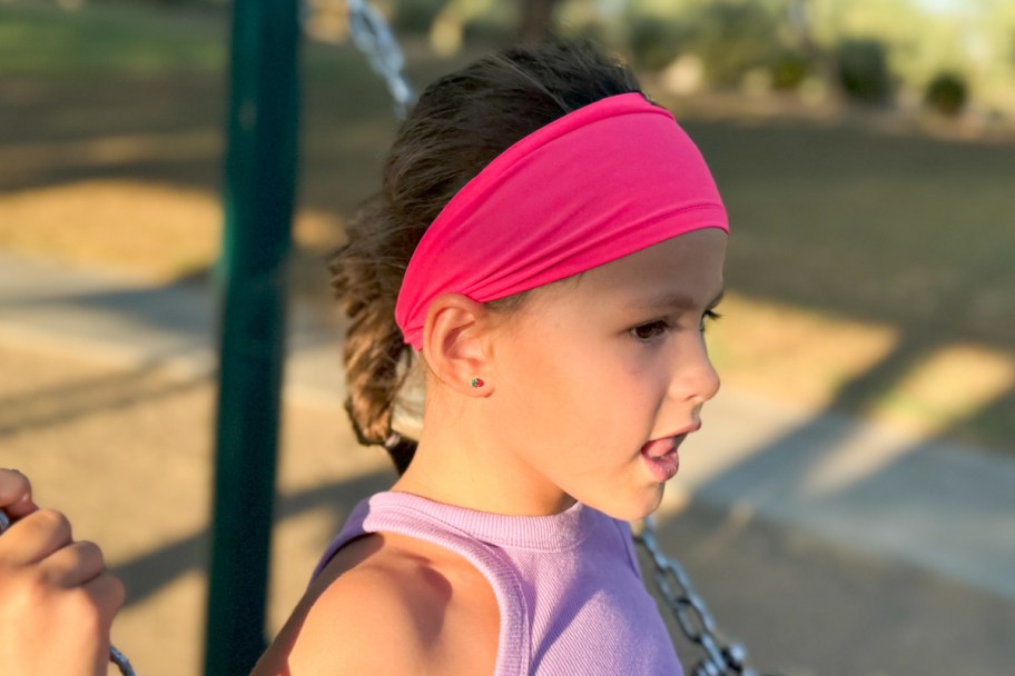 girl with pink headband on swing