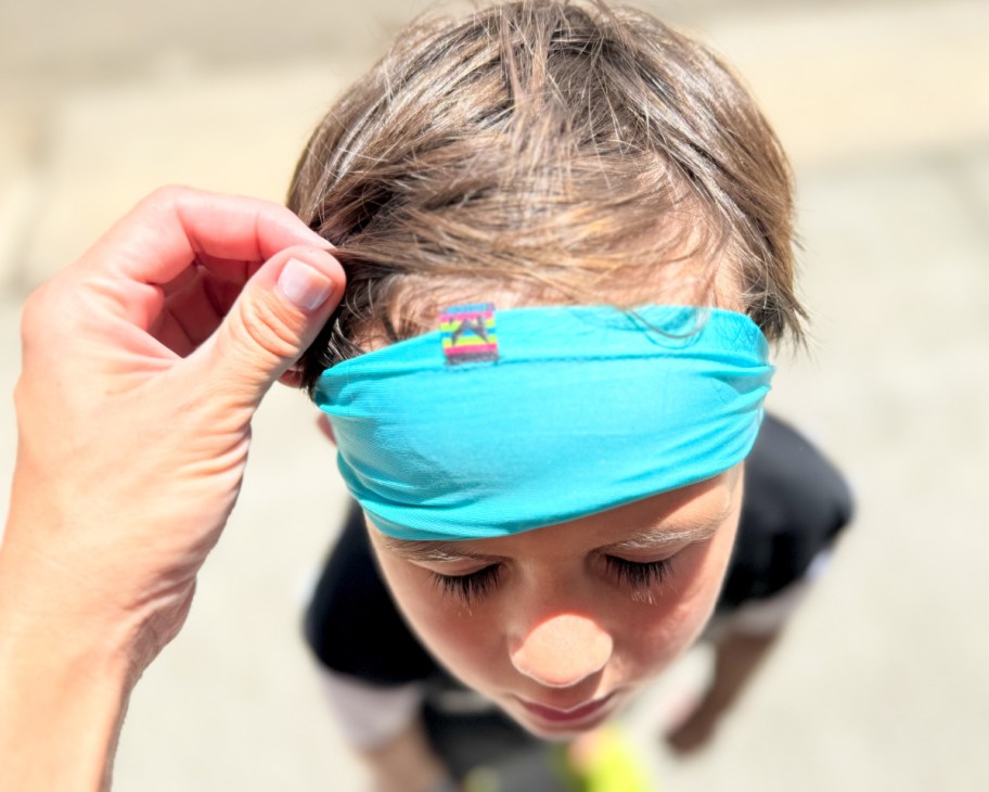 hand holding cooling headband on boys forehead