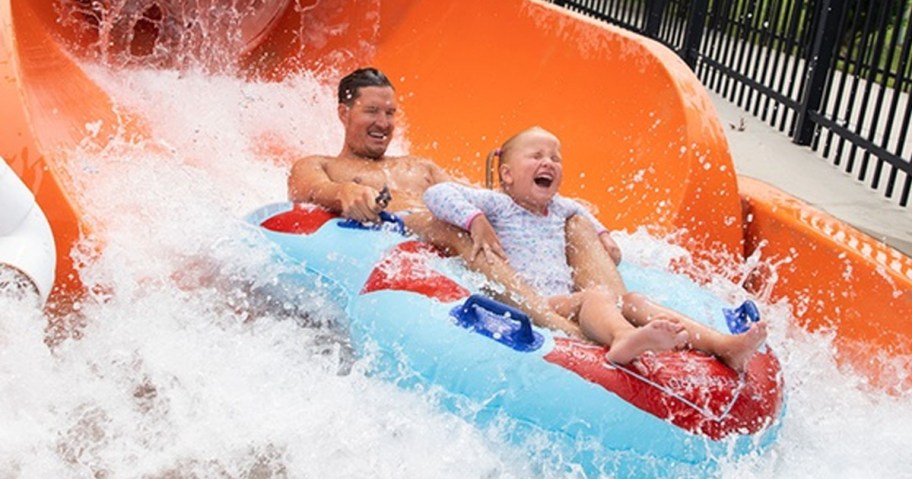 man and girl in pool float coming out of slide