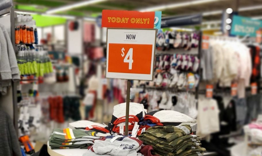 Old navy tee sale sign above a display table in a store