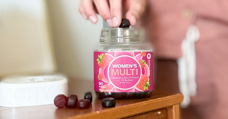person taking gummy out of olly bottle on table