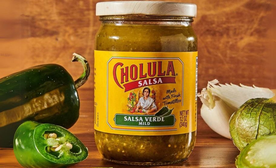 a jar of cholula salsa verde shown with peppers and tomatillos