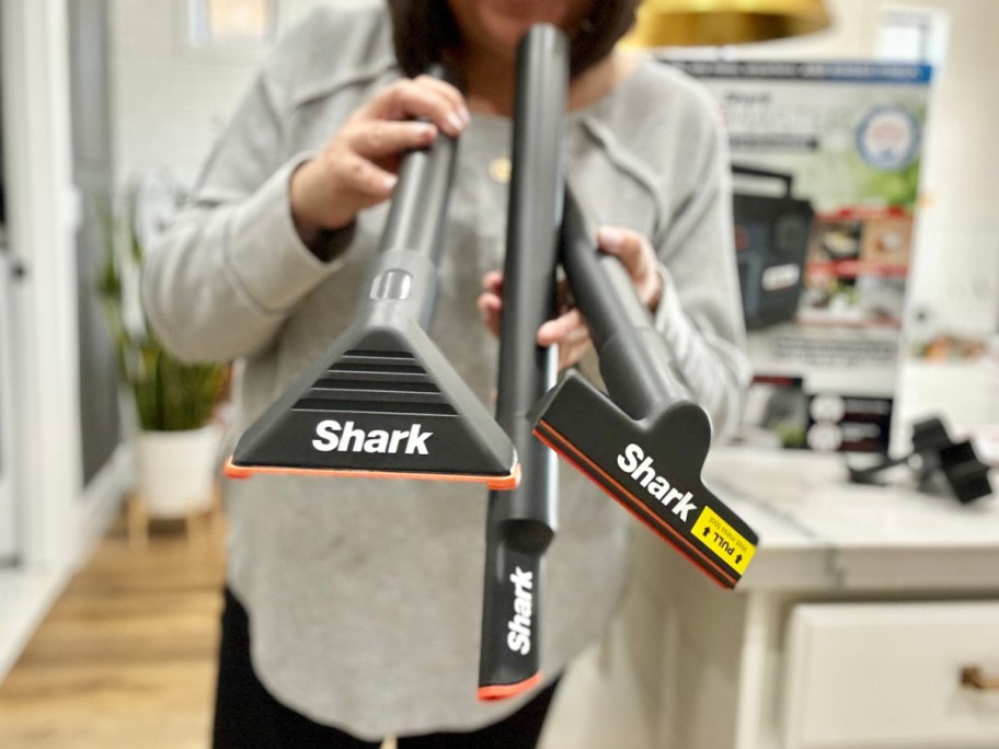 A woman holding a vacuum cleaner attachment