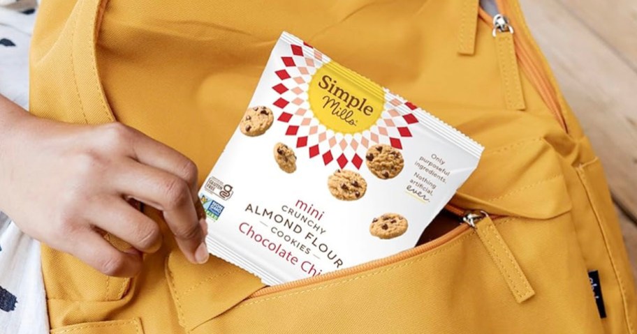 hand putting bag of cookies in yellow backpack