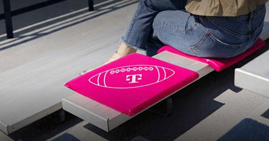 pink t mobile seat cushion sitting on bench with person sitting on one next to it