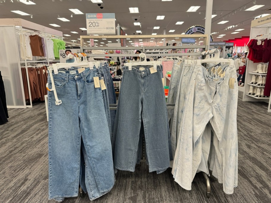 pairs of women's jeans hanging on a rack at Target with a sign that says "Recycle your old denim & get 20% off your purchase"