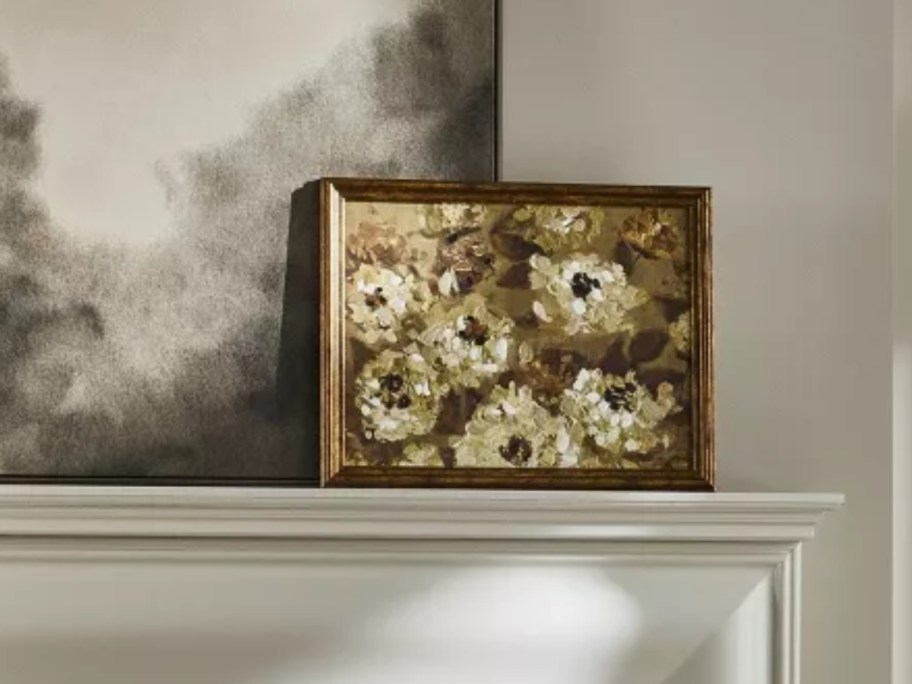 a framed canvas wall art floral piece on a mantel