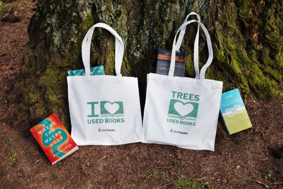 two canvas tote bags leaning against tree