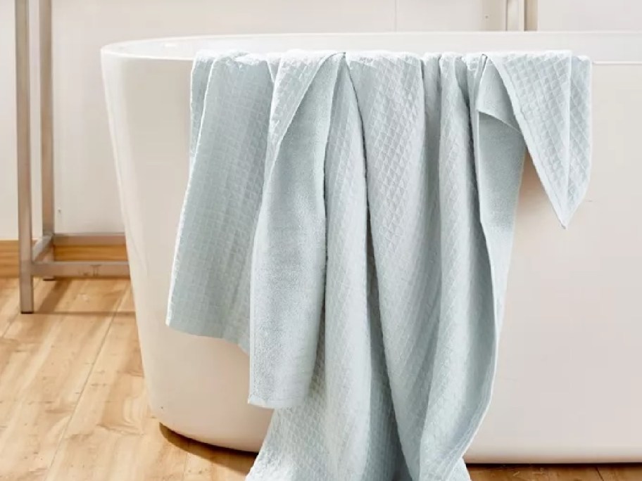 pale blue bath towel draped over a bathtub