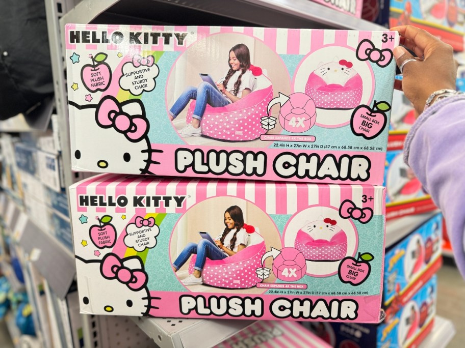 hand reaching for a pink and white box with a kid's Hello Kitty plush bean bag chair in it