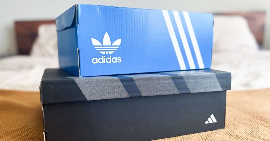 Two adidas shoe boxes on a bed