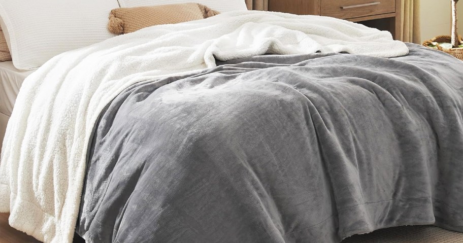 grey and white sherpa blanket on a bed