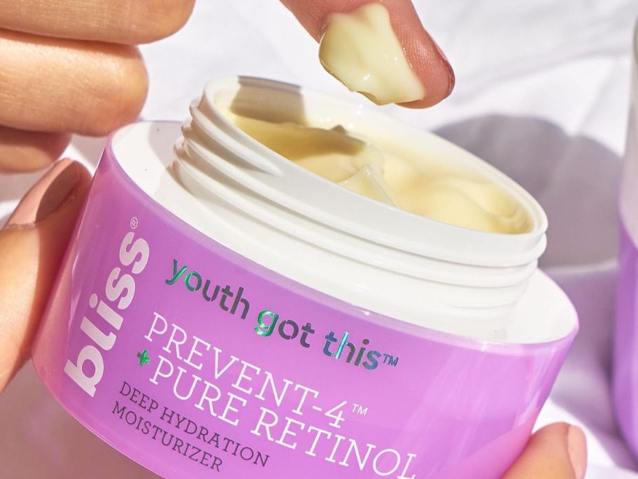 A finger taking some Bliss Youth Got This Retinol Moisturizer from the jar