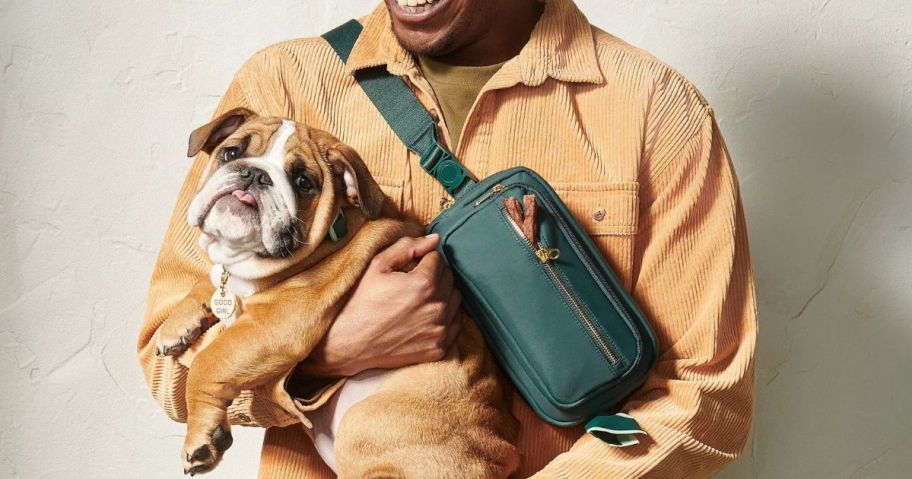 A man wearing a Cuddle Collab Dog Walker Belt Bag holding a cute dog