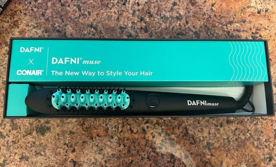 a turquoise and black power styling brush shown with packaging on a counter top