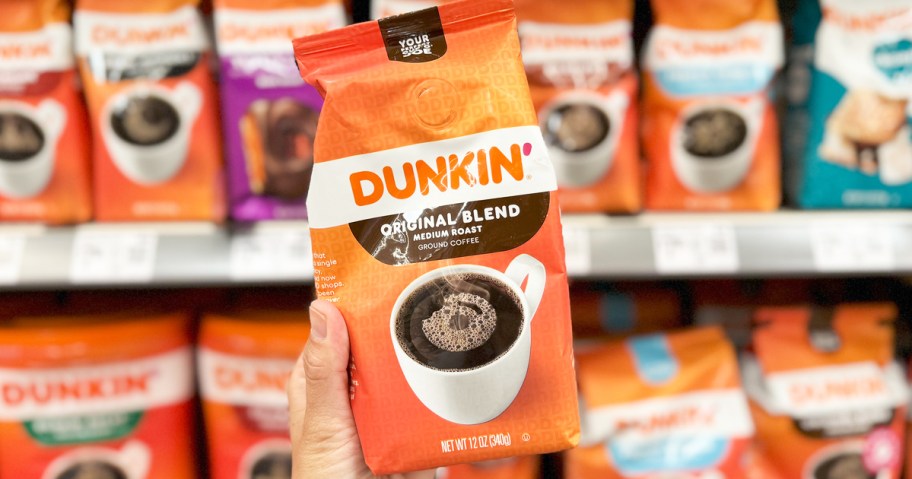 hand holding up a bag of Dunkin' Ground Coffee in store