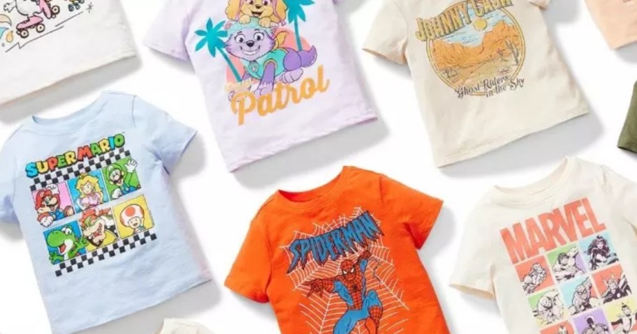 kid's character graphic t-shirts laid out at an angle, Spiderman, Paw Patrol, Super Mario, and more