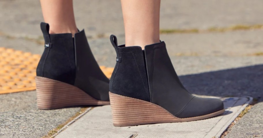 women's feet wearing a pair of black and brown wedge ankle boots