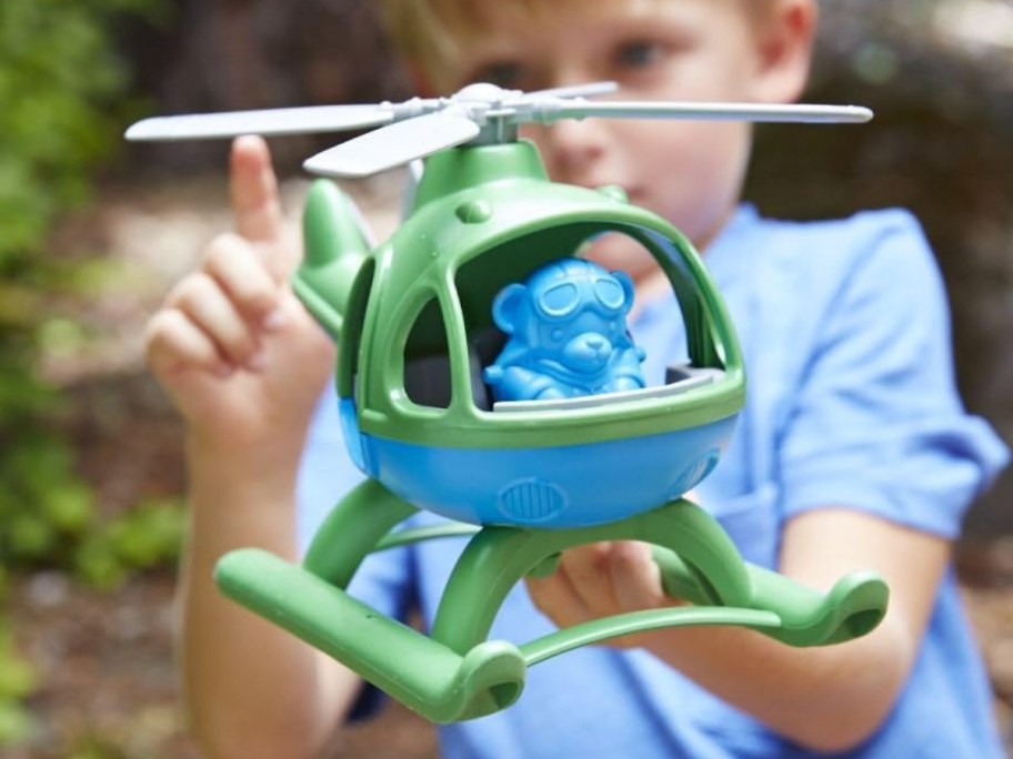 little boy in a blue shirt playing with a blue and green plastic helicopter toy