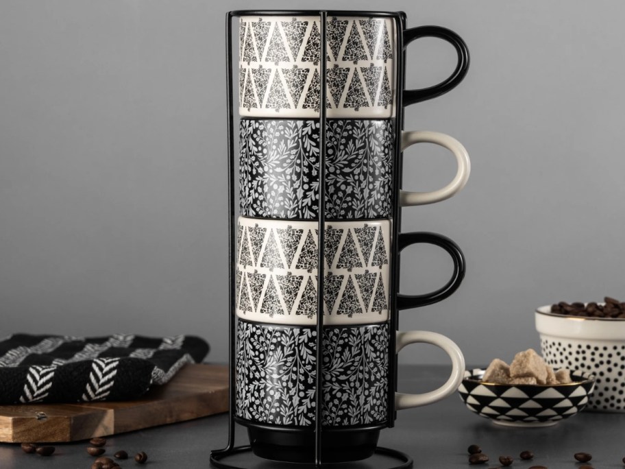 a stacking mug set in a metal rack with black and white Christmas trees and black and white holly leaves and berries print