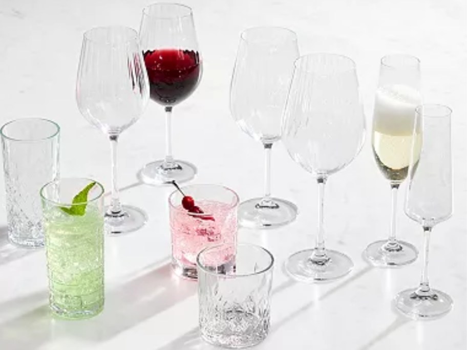 various drinking glasses, wine glasses, champagne glasses, some with drinks, some empty