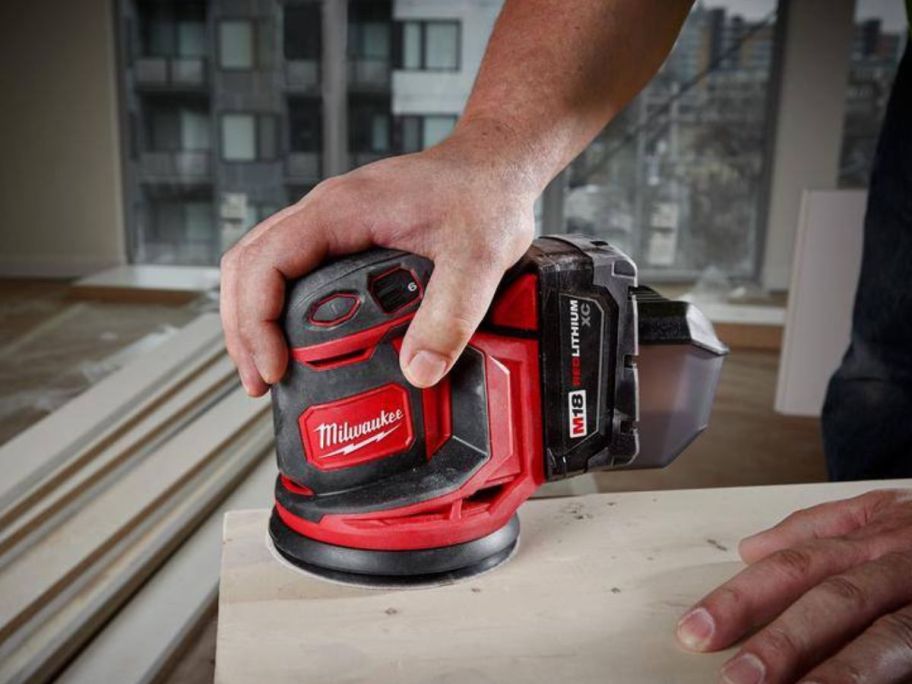 Hand using a Milwaukee M18 18V Lithium-Ion Cordless 5" Random Orbit Sander 