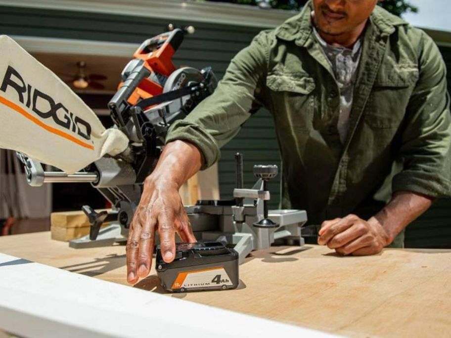 man working with tools grabbing a RIDGID 18V Lithium-Ion  4.0 Ah Battery