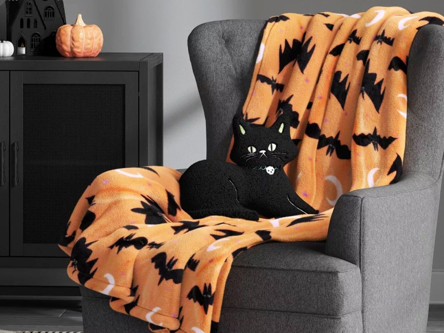 orange bat print throw blanket on a couch with a black cat pillow