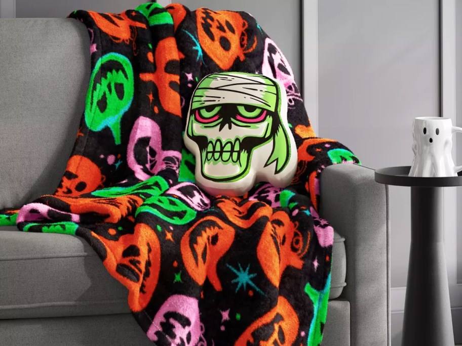 neon jack-o-lantern throw blanket with mummy head throw pillow on a couch