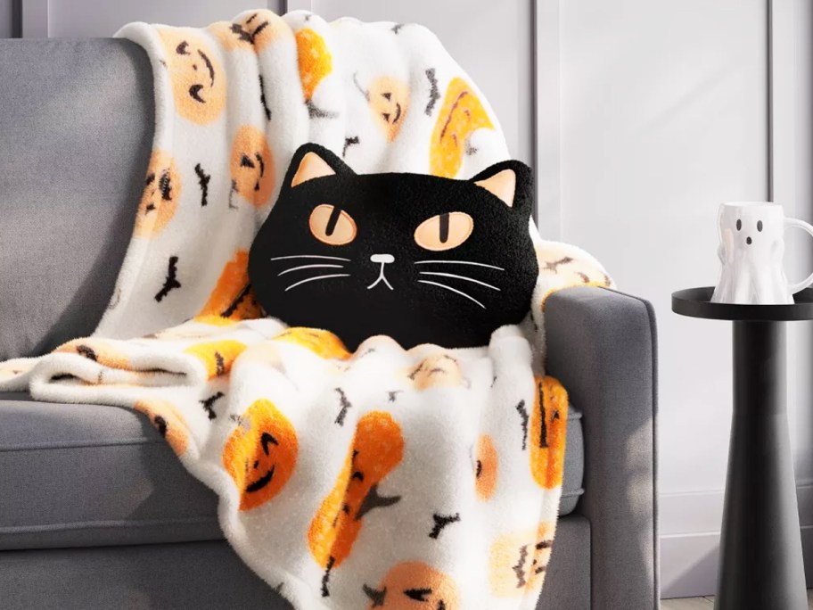 pumpkin print throw blanket on a couch with a black cat throw pillow