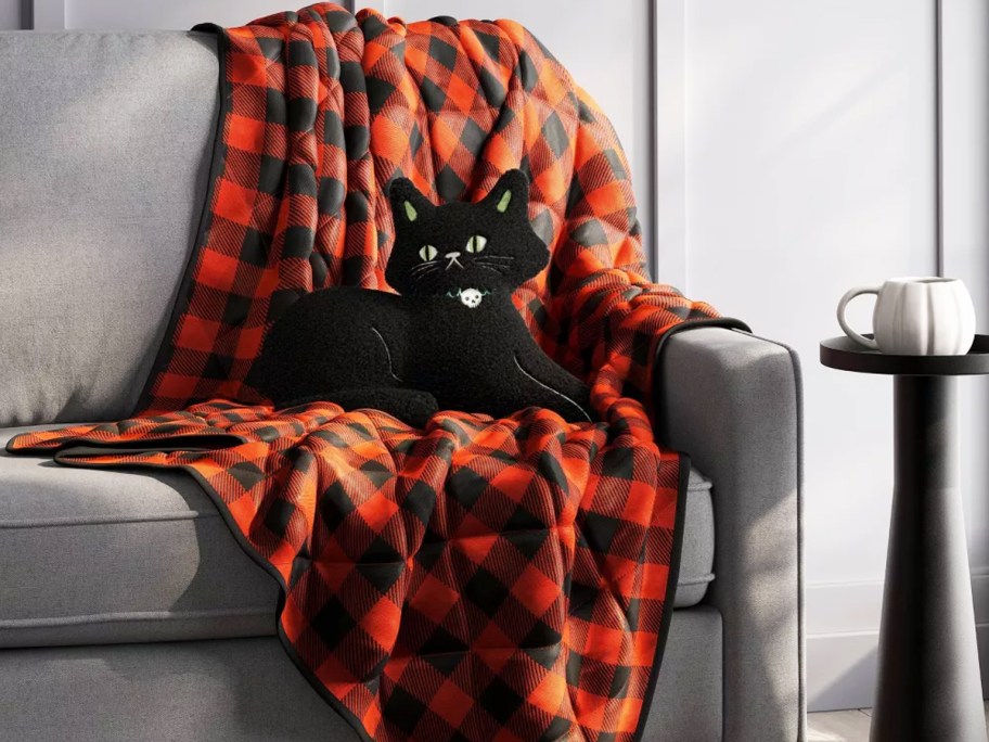 orange and black plaid throw blanket with cat throw pillow on a couch