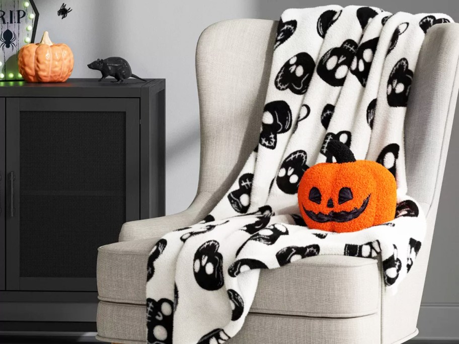 black and white skull print throw blanket on a chair with a pumpkin throw pillow