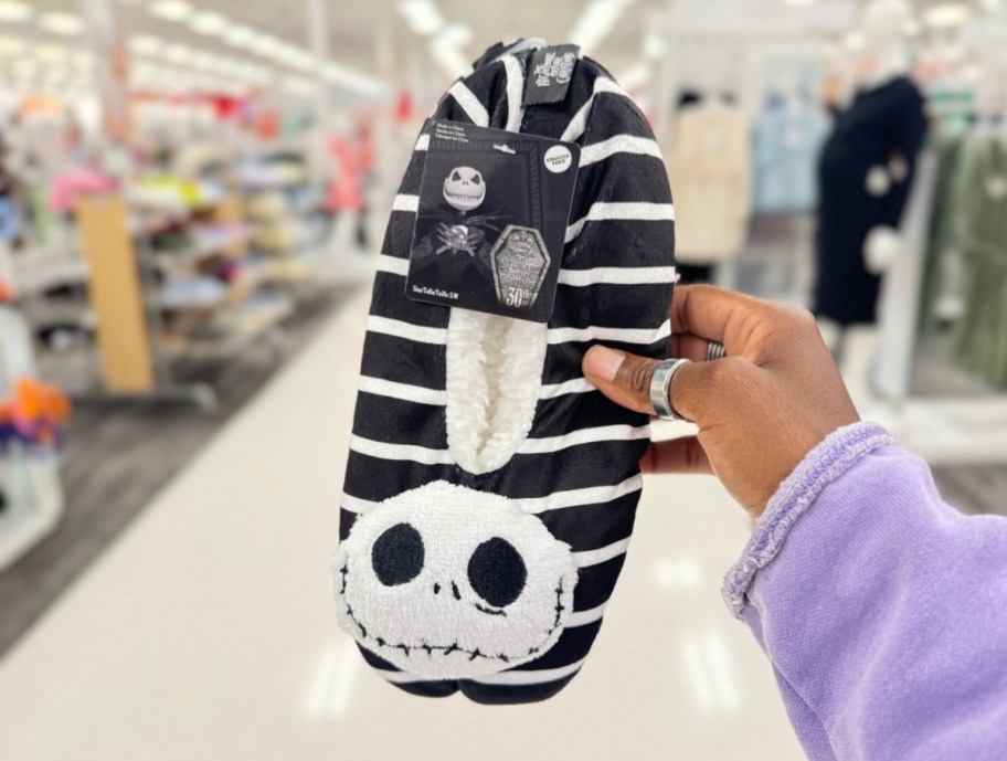 Hand holding up Jack Skellington Halloween slippers from Target