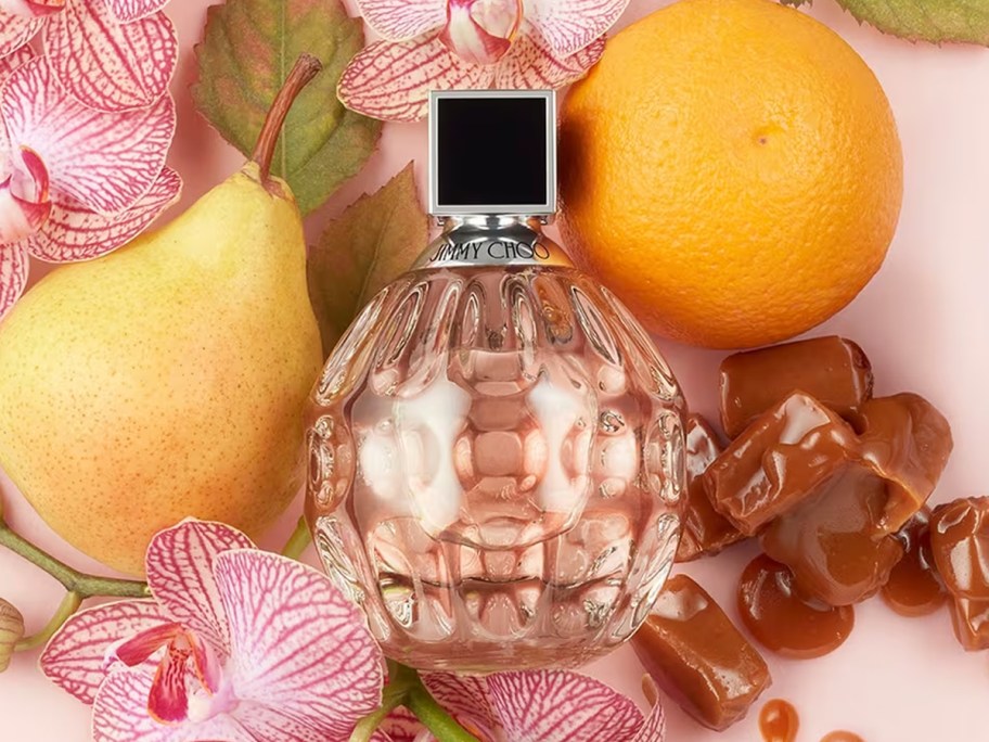 bottle of Jimmy Choo perfume surrounded by flowers and fruits