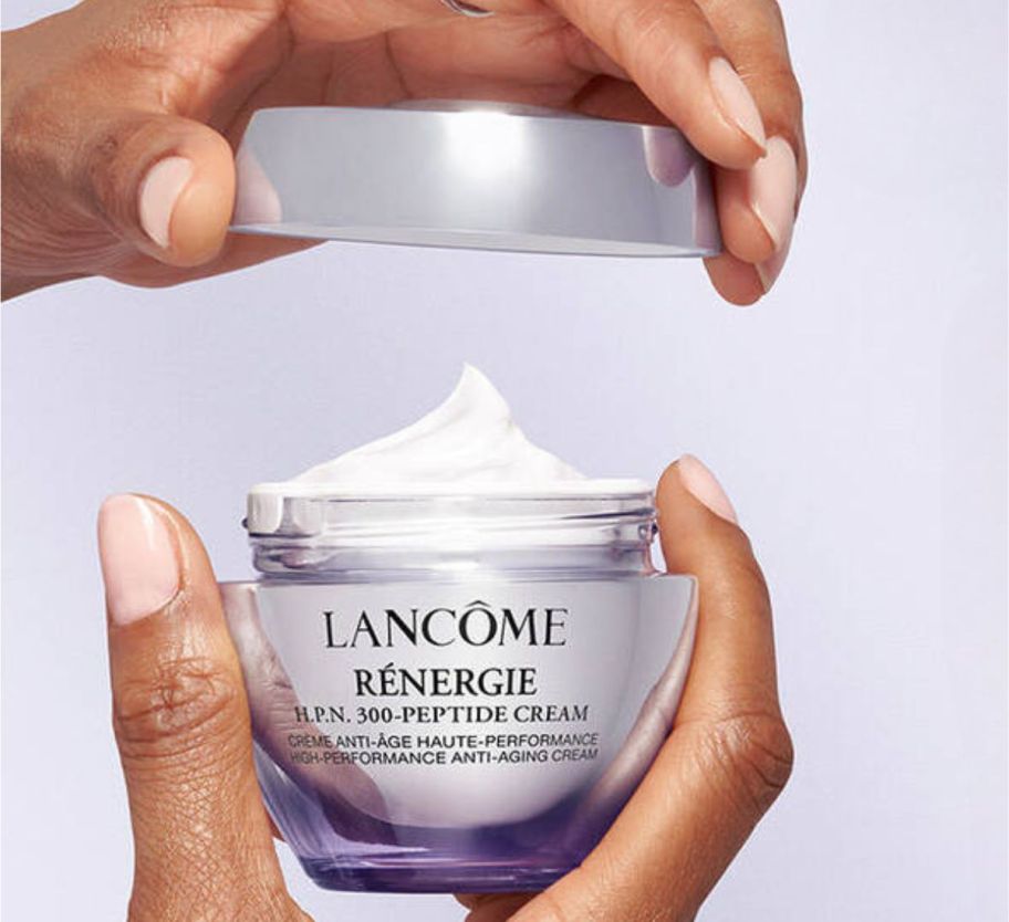 a womans hands removing the lid from a jar of Lancome moisturizer