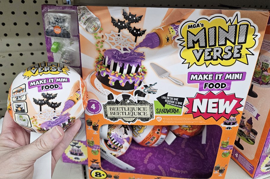 hand holding up MGA's Miniverse Make It Mini Food Halloween surprise ball next to store display