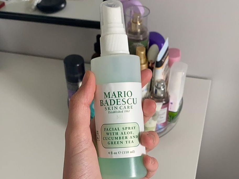 Hand holding a bottle of Mario Badescu Face Spray