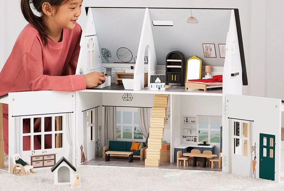 girl playing with wooden dollhouse