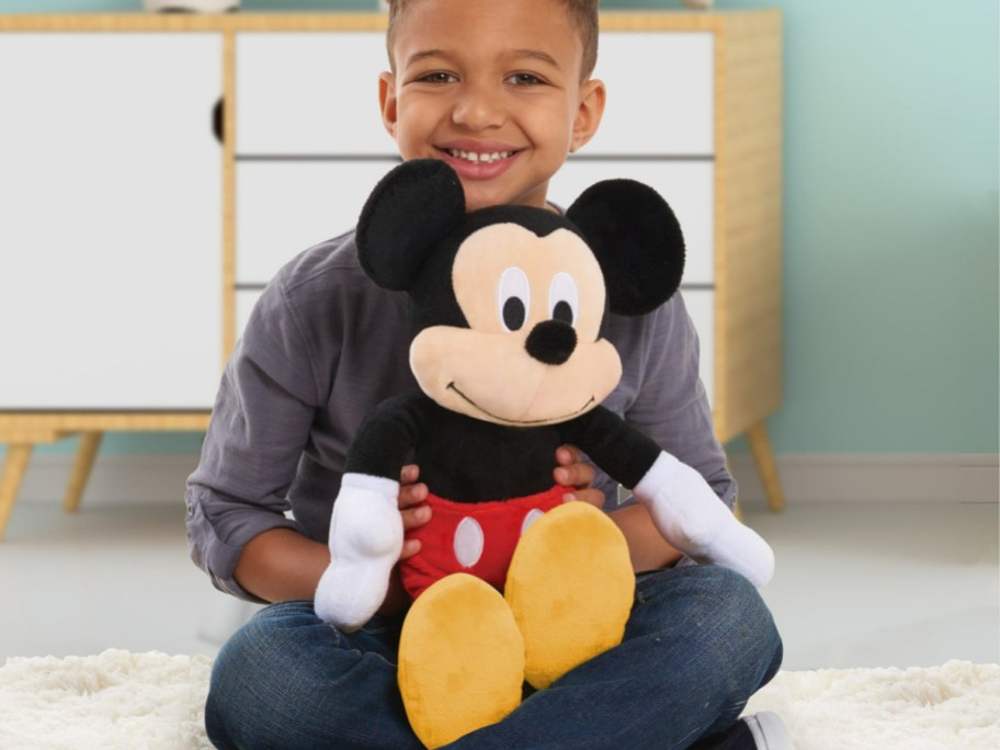 A kid holding a Mickey Mouse plush doll.